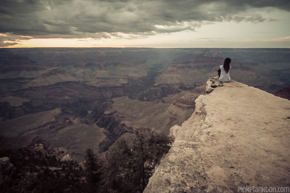 girl sitting on edge of the Grand Canyon at sunset