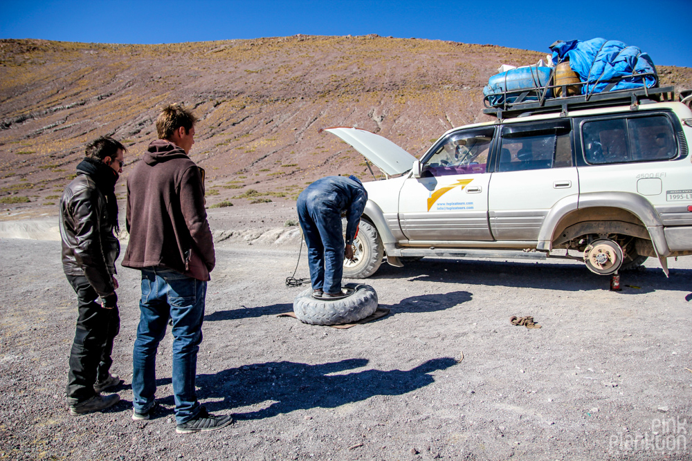 fixing a flat tire on 4WD jeep in Bolivia's desert