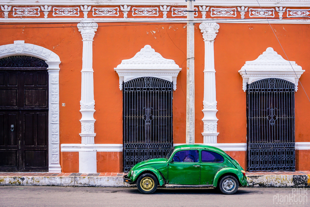 colorful orange buildings and green old school car in Campeche
