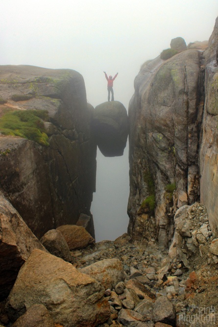 woman standing on Kjeragbolten in clouds in Norway