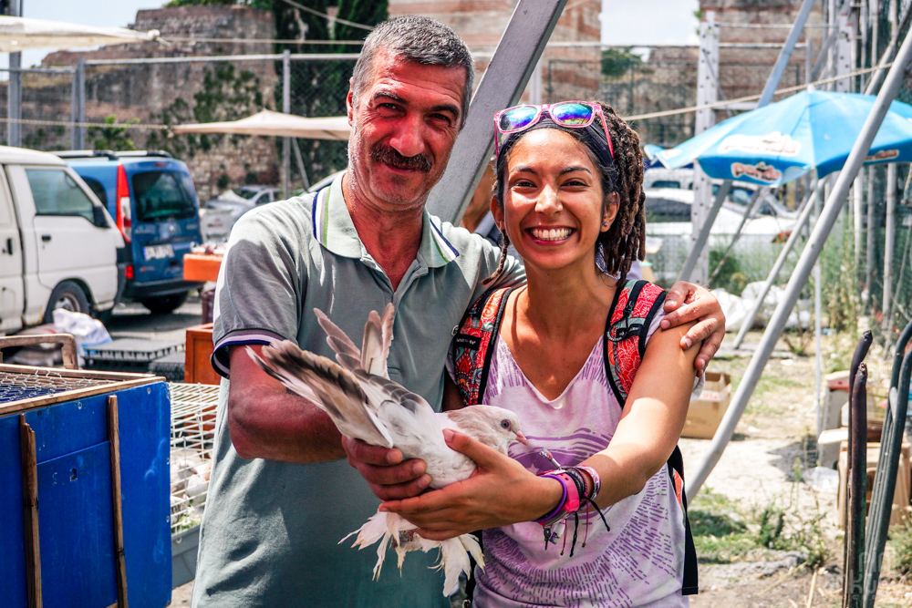 Man and tourist holding up pigeon at the Istanbul bird market