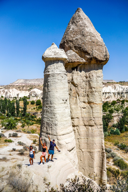three travelers posing in front of penis-shaped rock formations in Love Valley in Cappadocia, Turkey