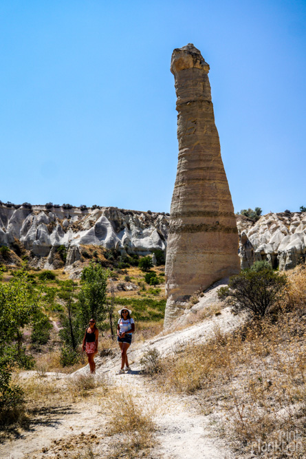 two girls posing in front of a penis-shaped rock in Love Valley in Cappadocia, Turkey