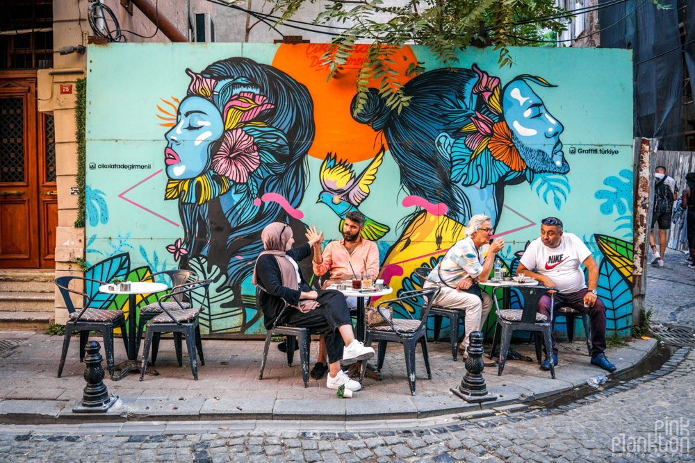 people sitting at coffee shop patio with street art in Balat, Istanbul
